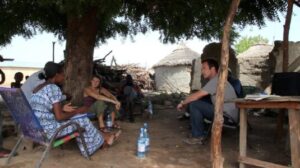 students with local community under tent