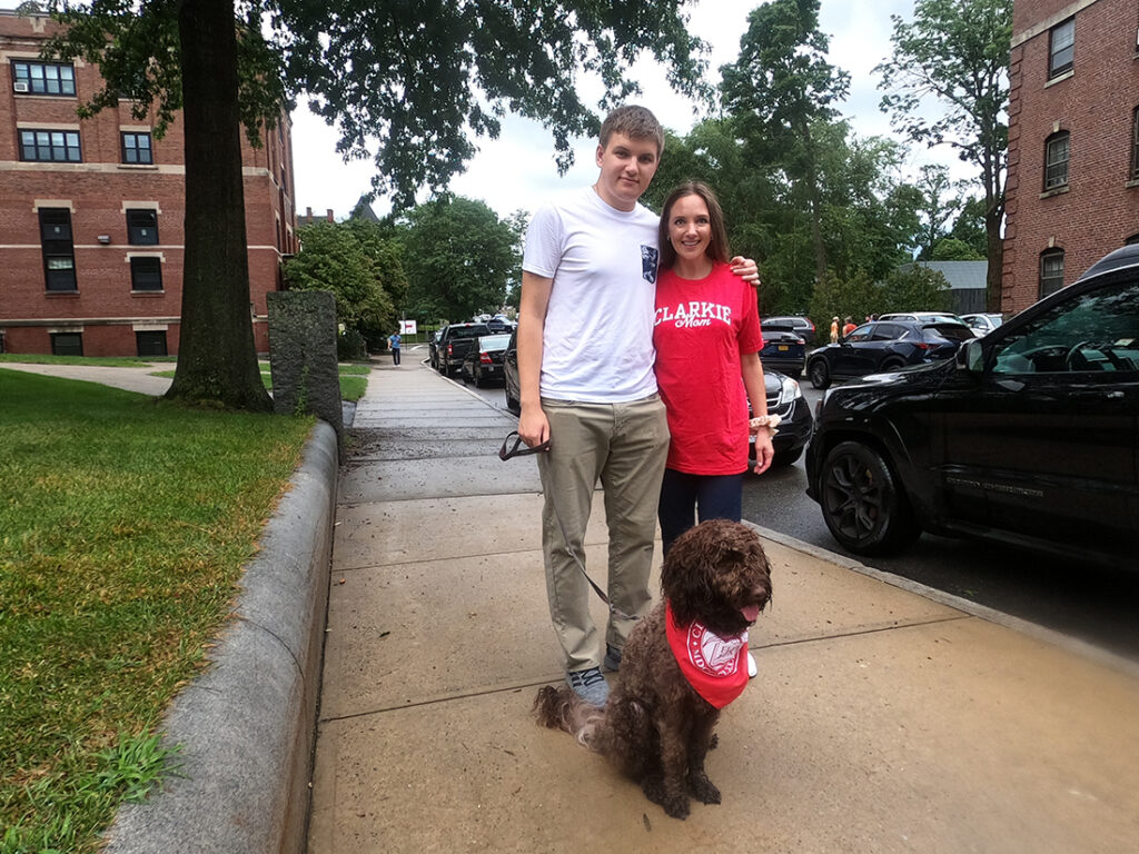 Clark University student and his mother pose with their dog.