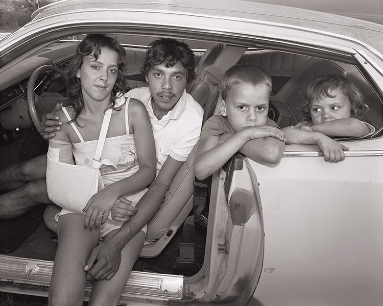 Parents and two children look out from a car, 1983