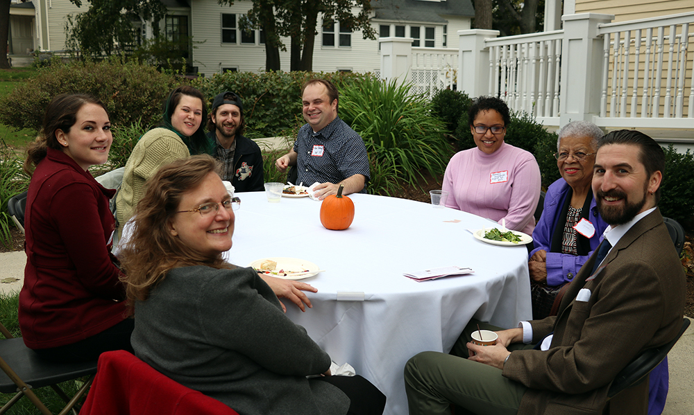 English alumni and faculty seated around table outside