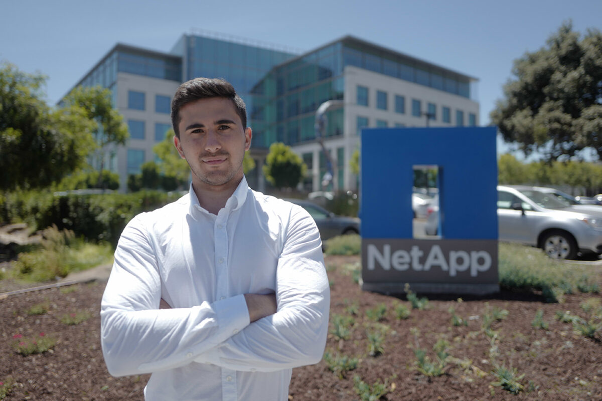 Teodor Nicola-Antoniu standing in front of NetApp sign outside building