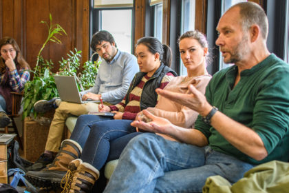 Dave Wilkie, seated, speaks to class, with several students seated beside him