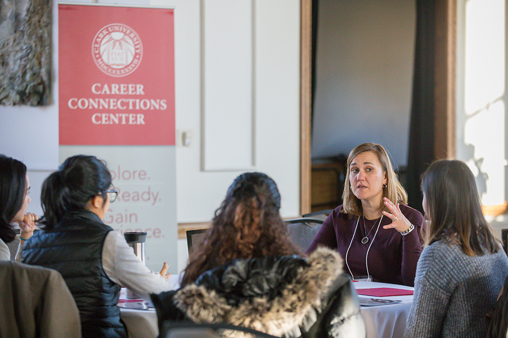 Students talk with alum at table.
