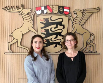 Lizzie Lloyd, left, and Jutta Niemann standing in front of crest