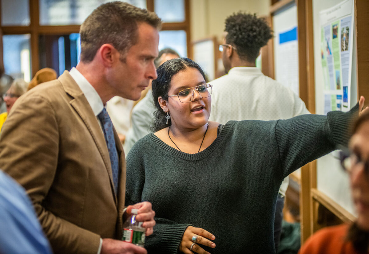 Student talking to faculty member about poster