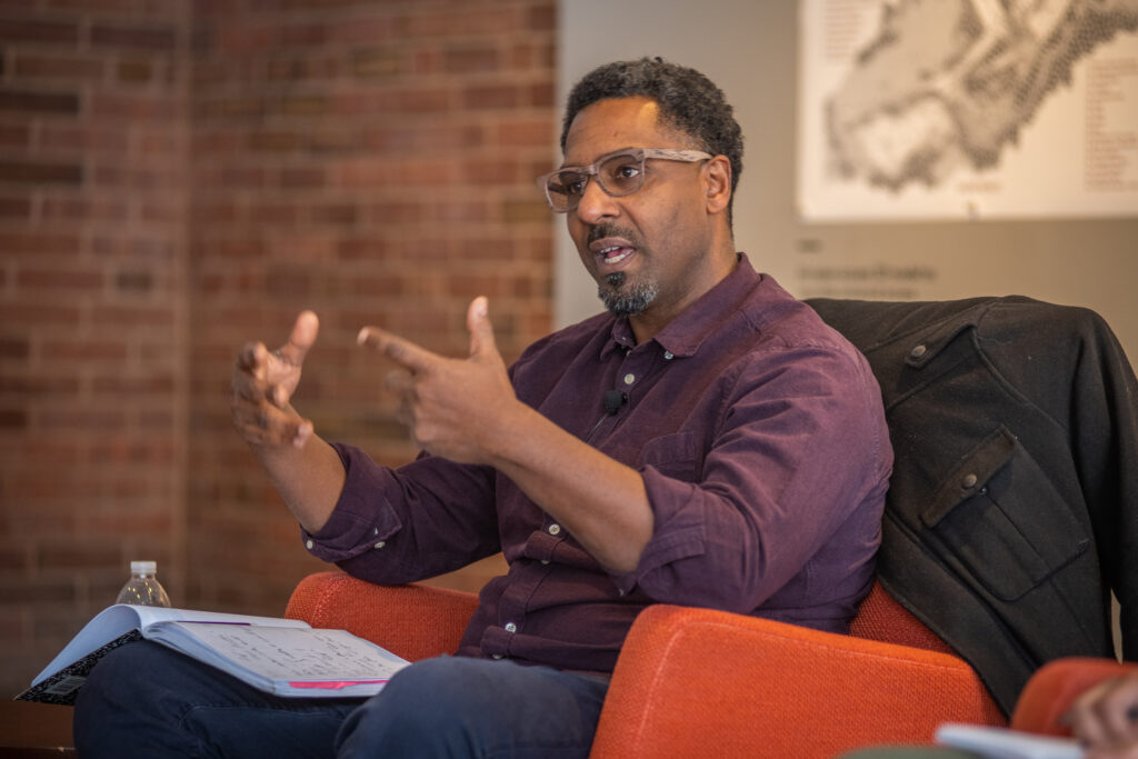 professor sits in chair while lecturing