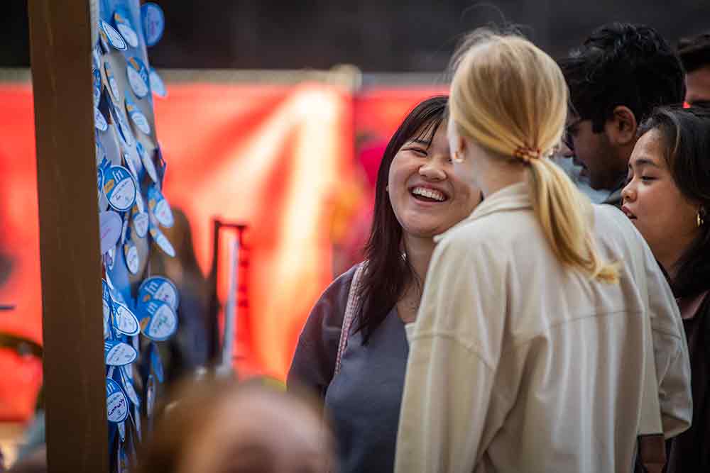 A student laughing in front of a participatory board filled with positive statements created during #FreshCheckDay, Clark University