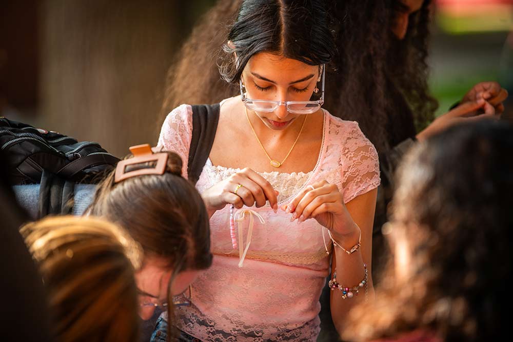 A student participates in a beading activity during #FreshCheckDay, Clark University
