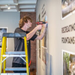 Dan Gillooly '25 helps hang Professor John Garton's Digital Bomarzo Show.