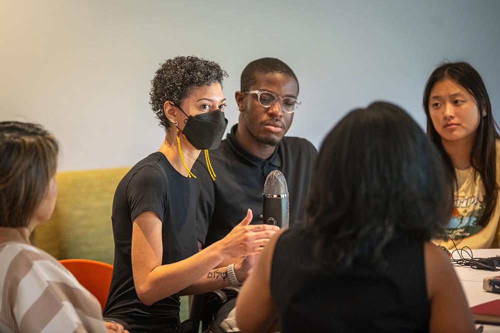 Chanda Prescod-Weinstein seated, leading a small group discussion with students