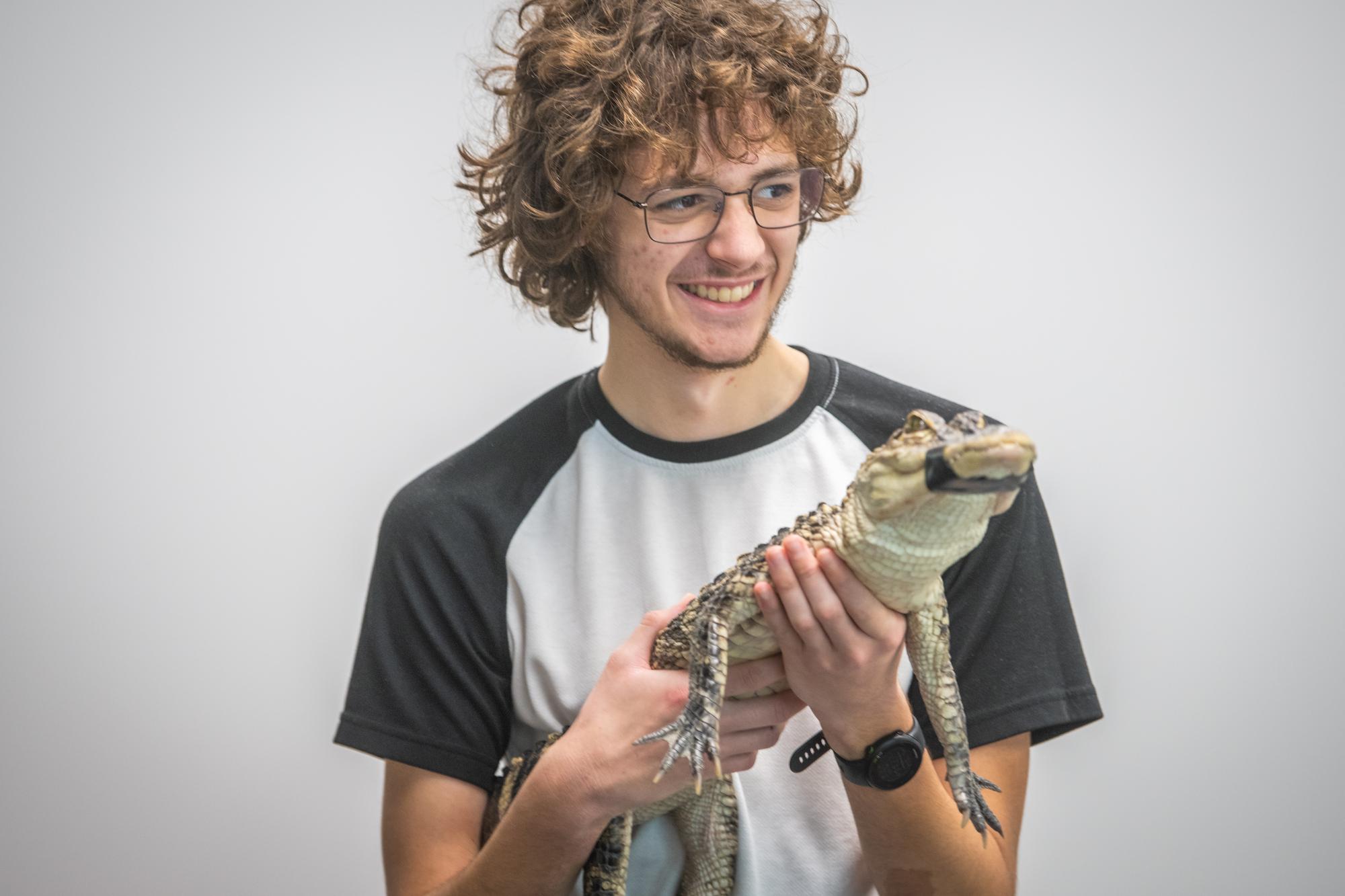 a student holds a small alligator