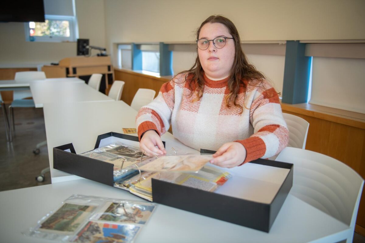 student flips through binder of postcards