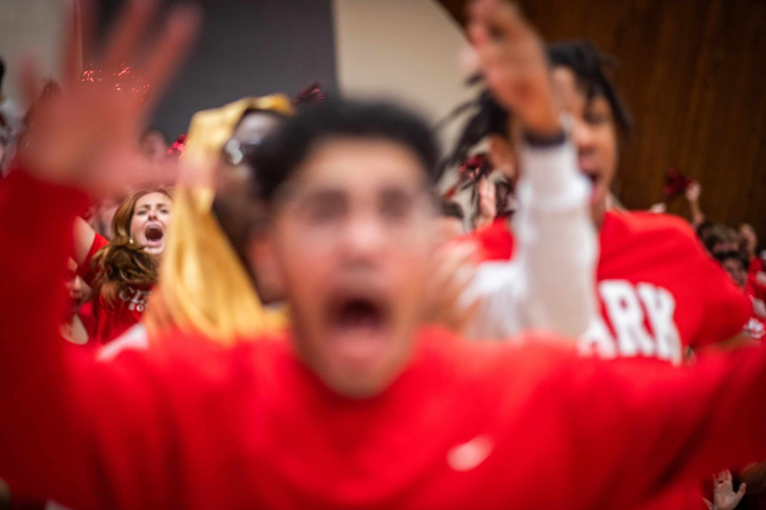 A crowd of students cheering during a mens basketball finals game with a blurred forground
