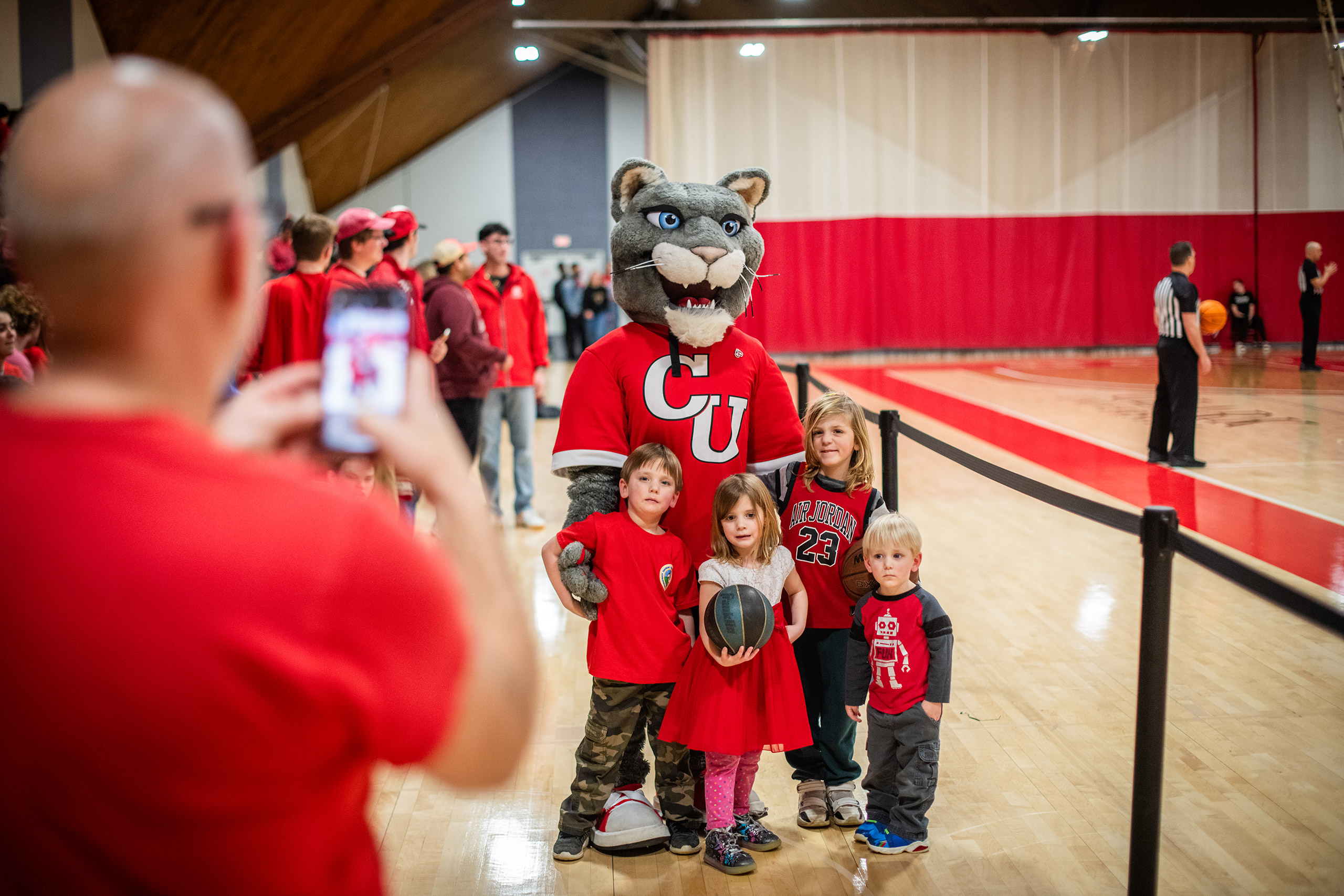 A group of children poses for a picture with the cougar mascot during the mens final game