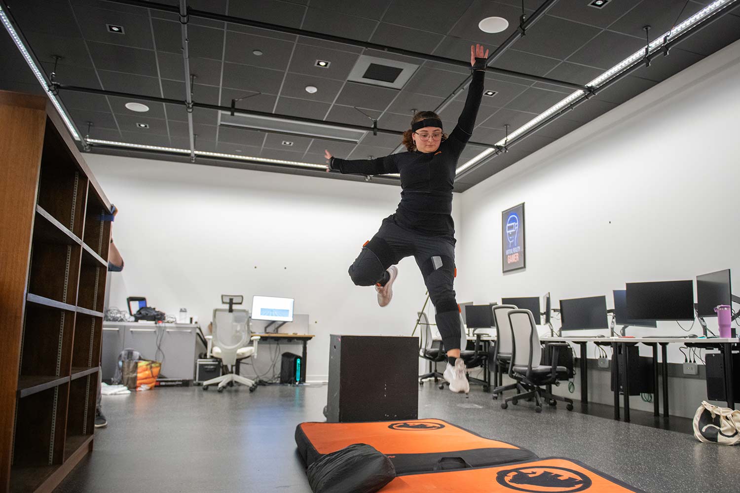 A student jumps onto a mat in the motion capture studio.