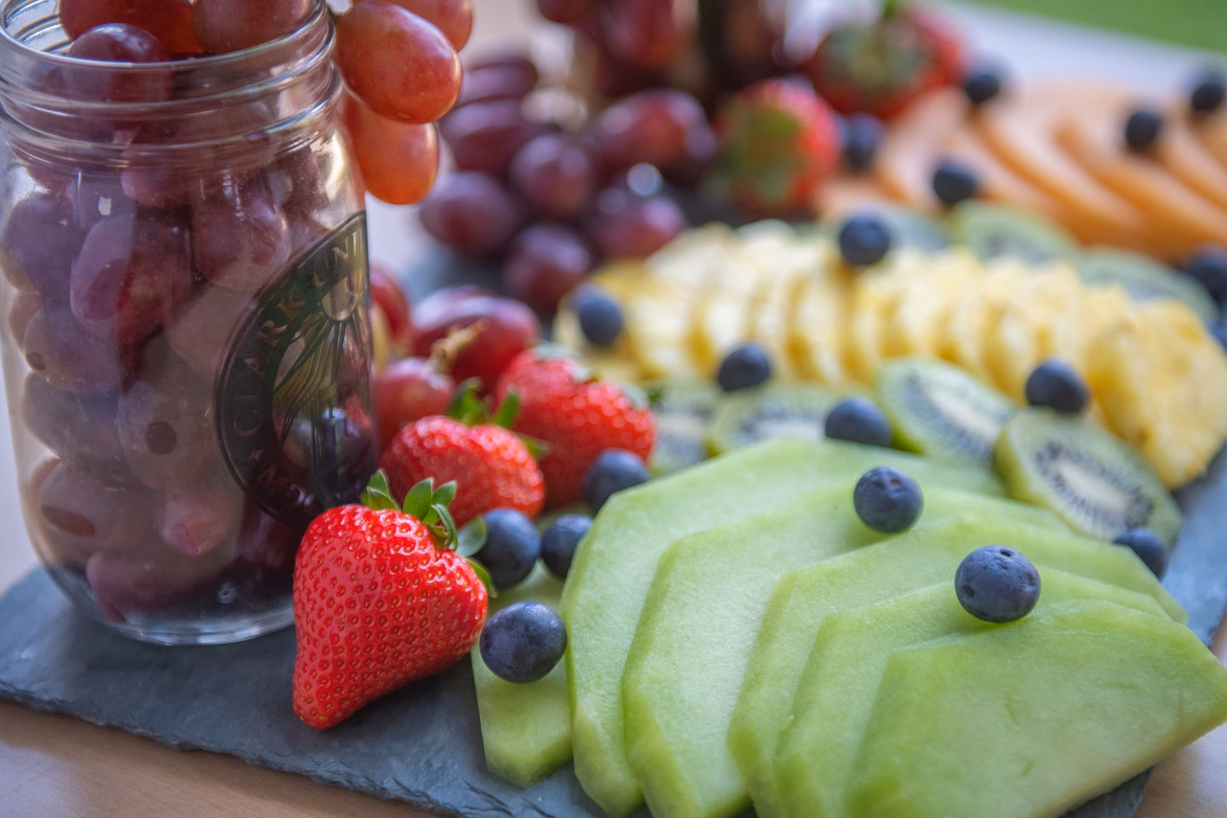 display of fruit including honeydew melon, strawberries, blueberries, and grapes