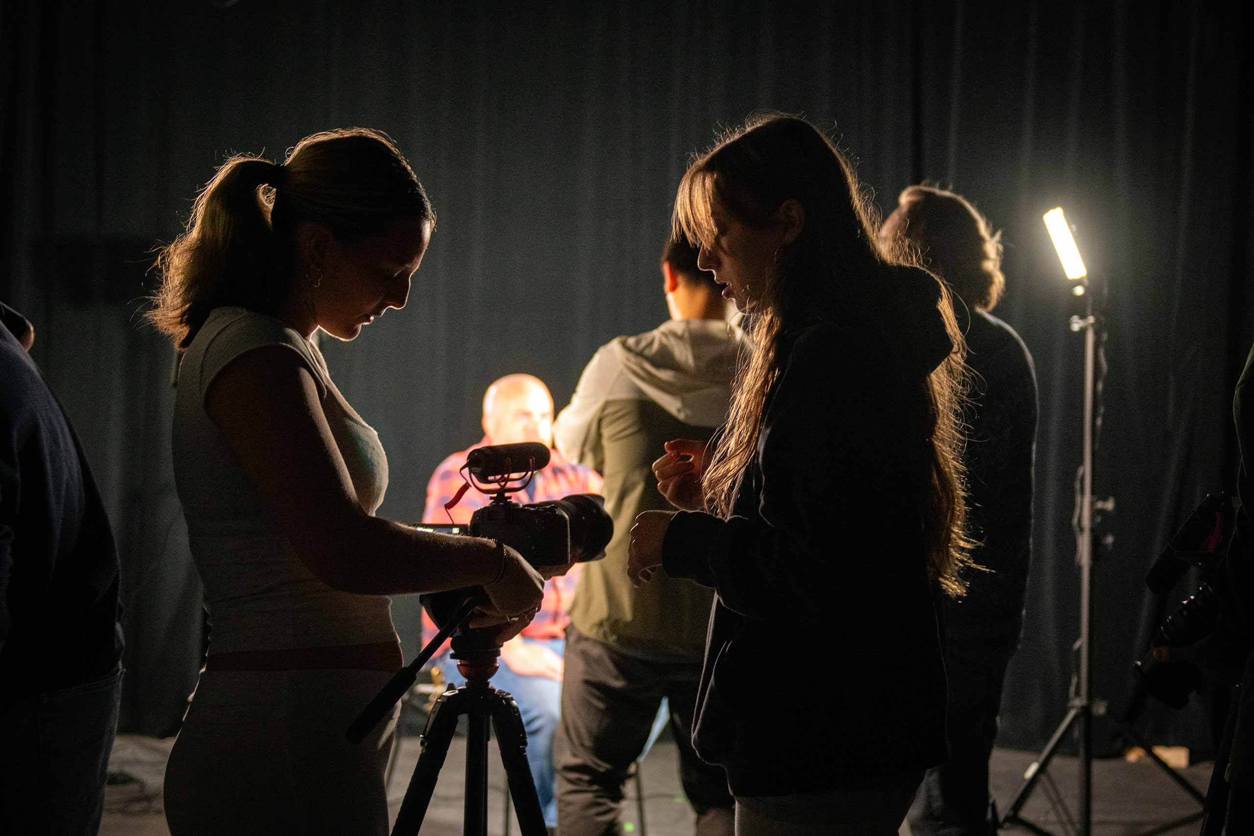 Students silhouetted by set lighting, set up tahe digital film camera, Clark University