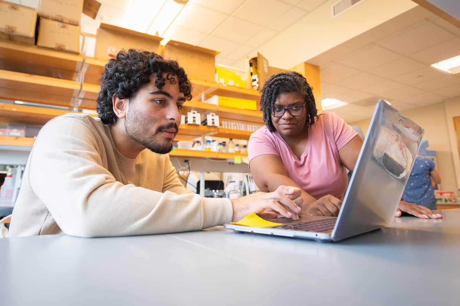 A student working with a professor to record data for a biology lab, Clark University