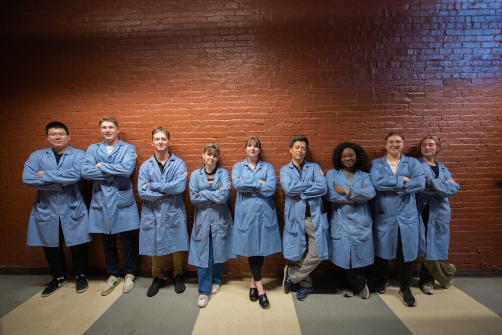 Katelynn Humphrey ’25, fifth from left, with her colleagues in the lab of Professor Julio D‘Arcy, sixth from left. (Photo by Steven King, university photographer)