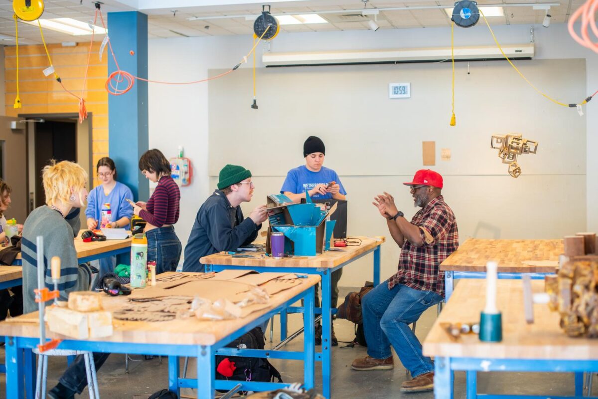 students and professor around workbench