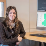 student poses for photo by computer