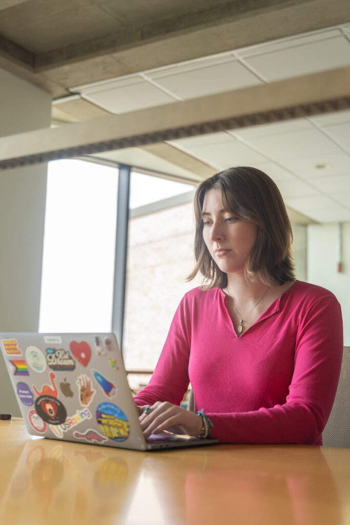 student works on laptop in library