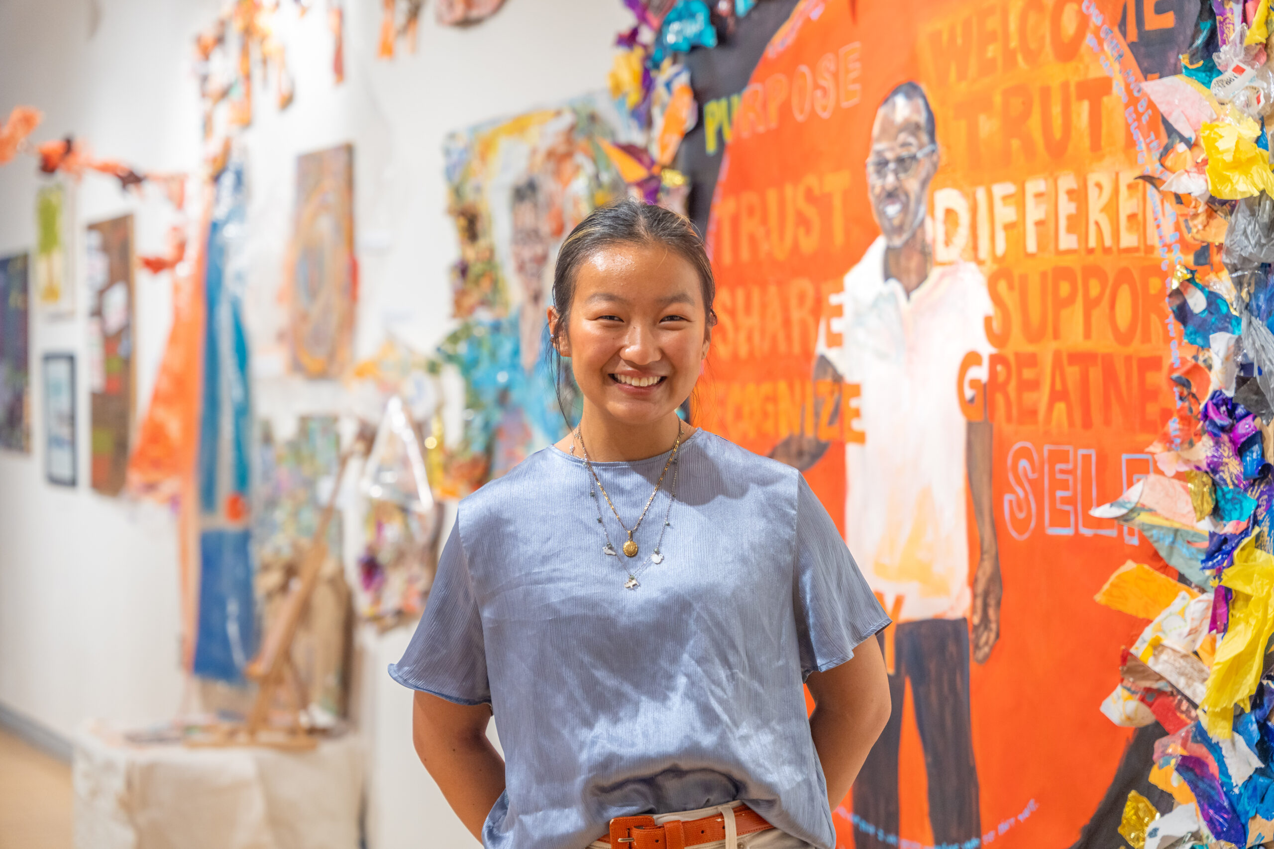 student poses for photo with art