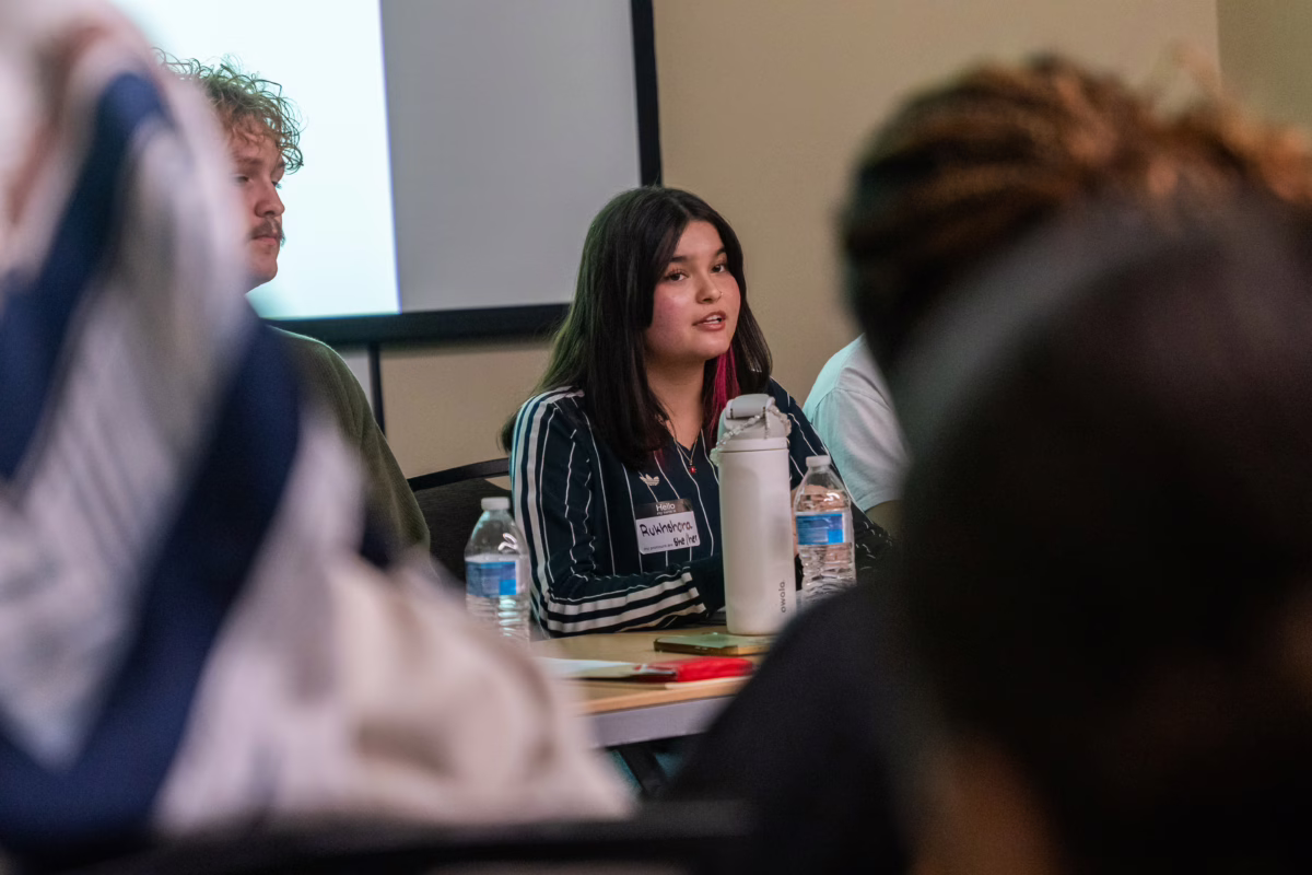 student sits at table for panel discussion