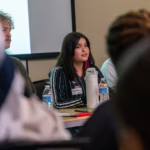 student sits at table for panel discussion