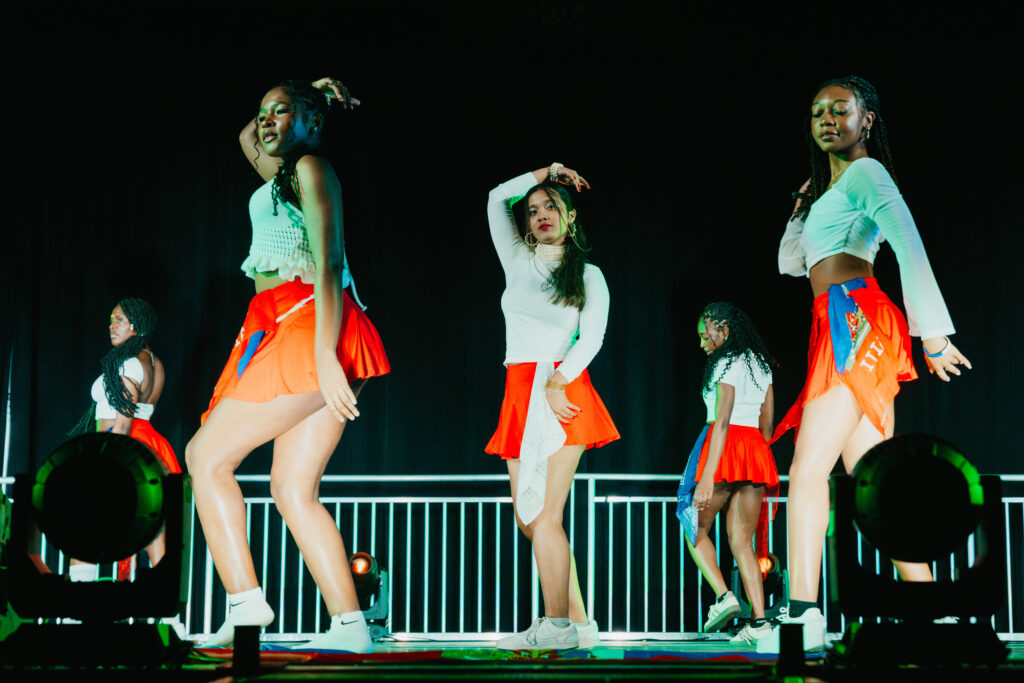 three students dance on stage