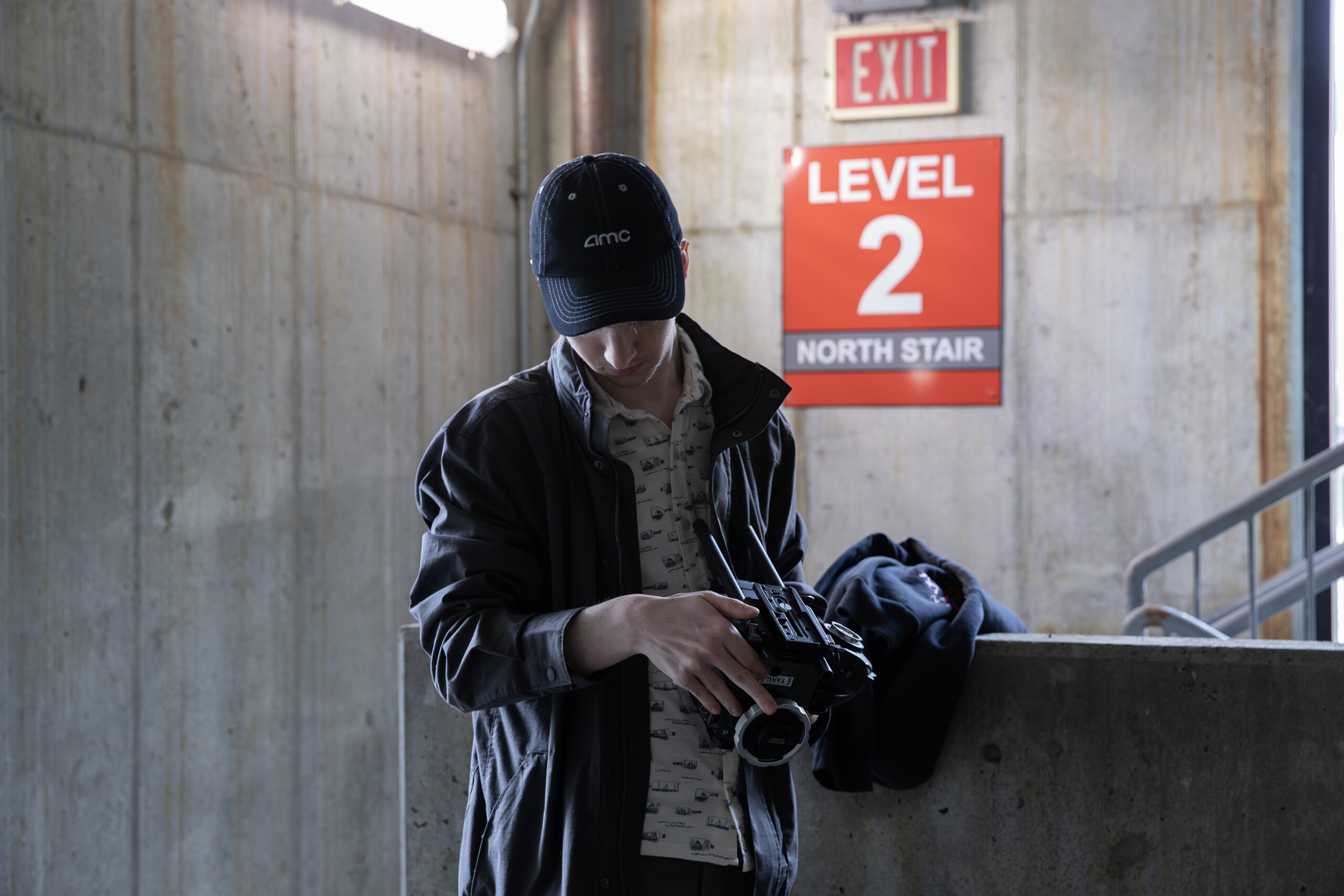 student holds camera in stairwell