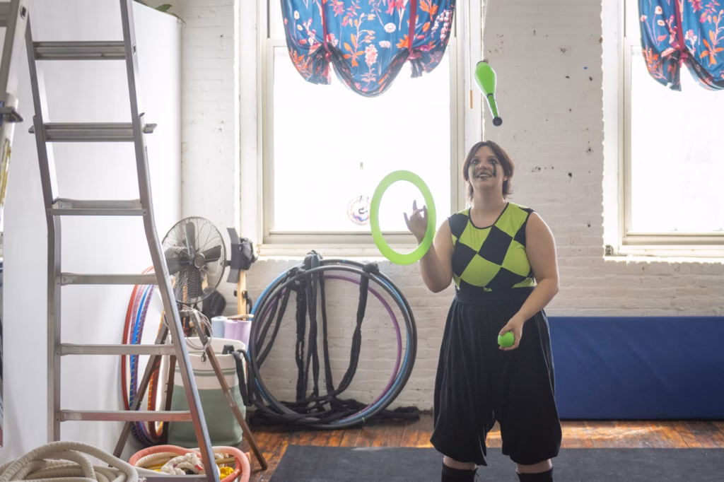 student juggling in green and black outfit