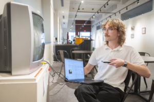 student with tv game in gallery