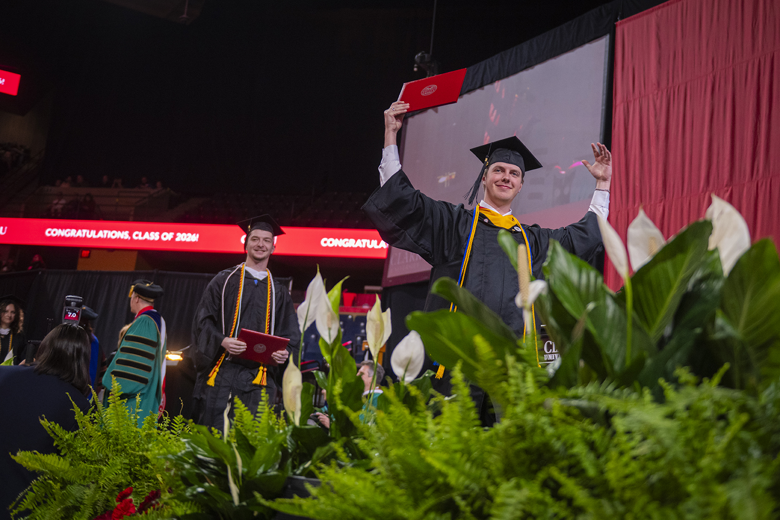 Male student holds diploma up after receiving it