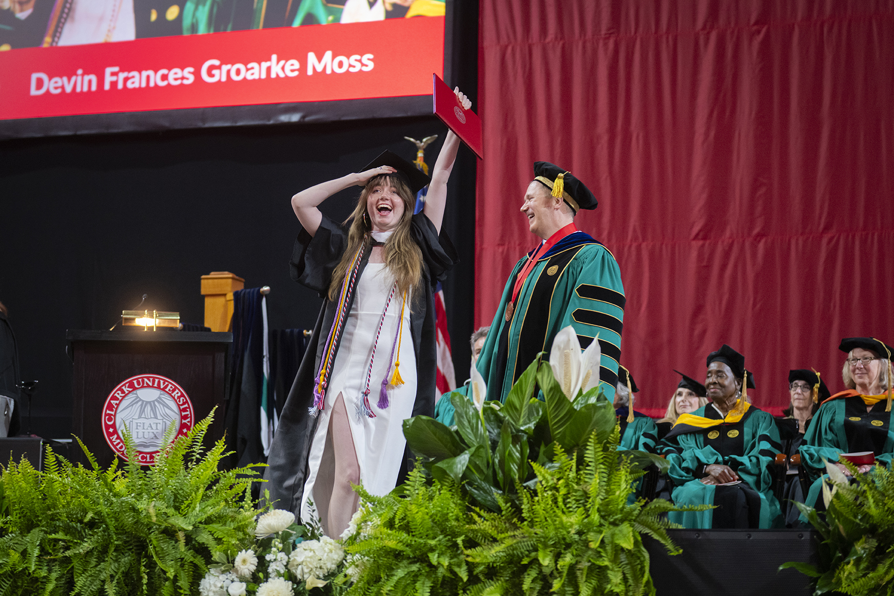 Student holds diploma up in the air