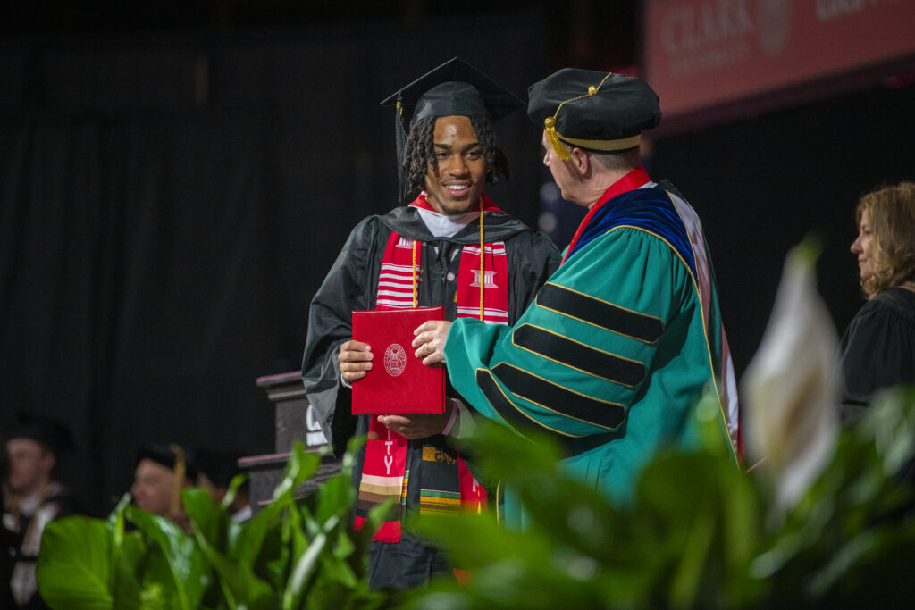 student receives diploma on commencement stage
