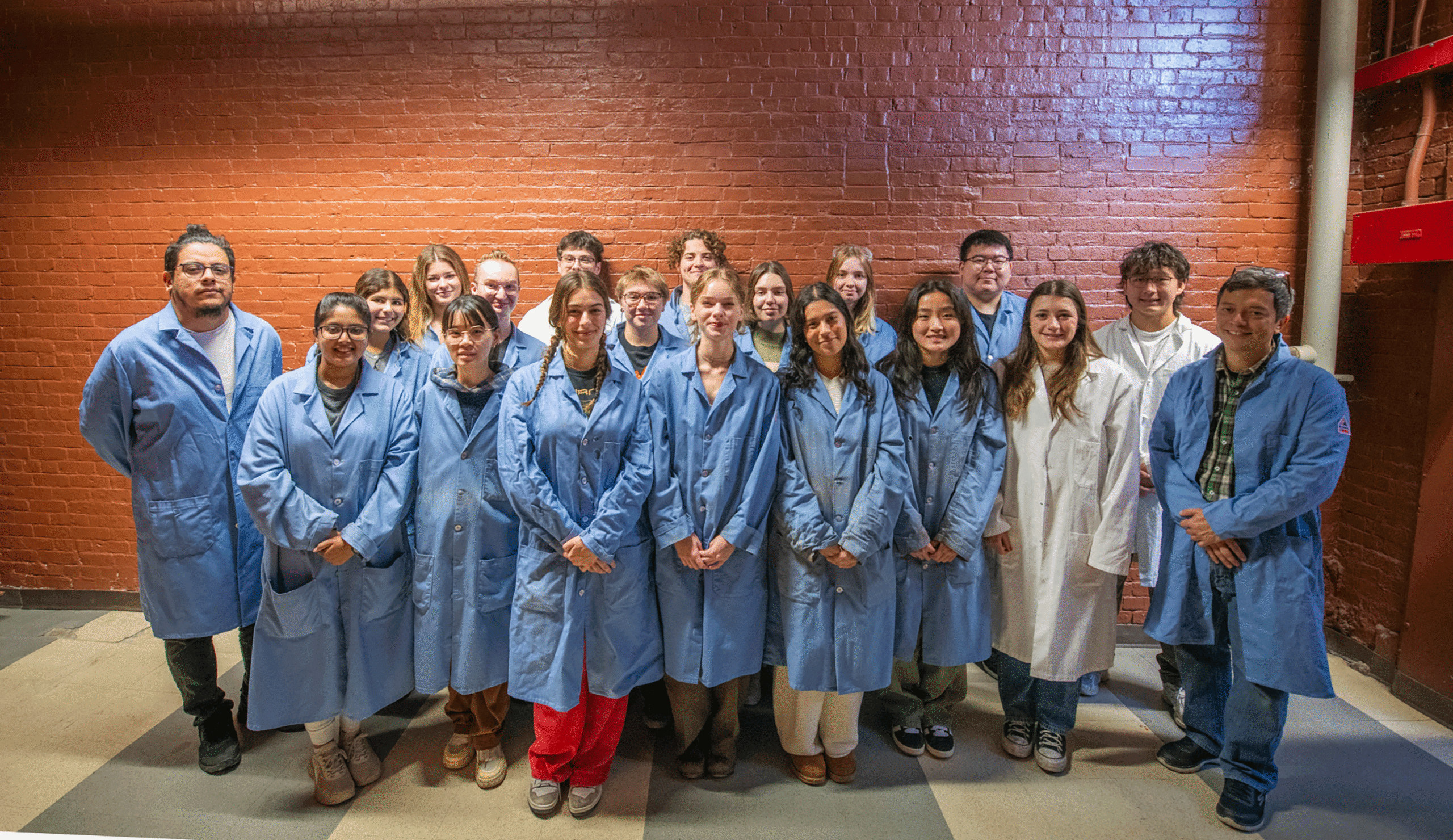 Professor Julio D'Arcy and his students pose near a brick wall.