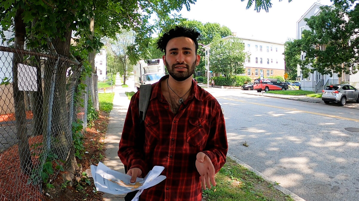 Garren Kalter stands on sidewalk holding papers in his hand