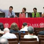 four people sit at table with microphones during panel
