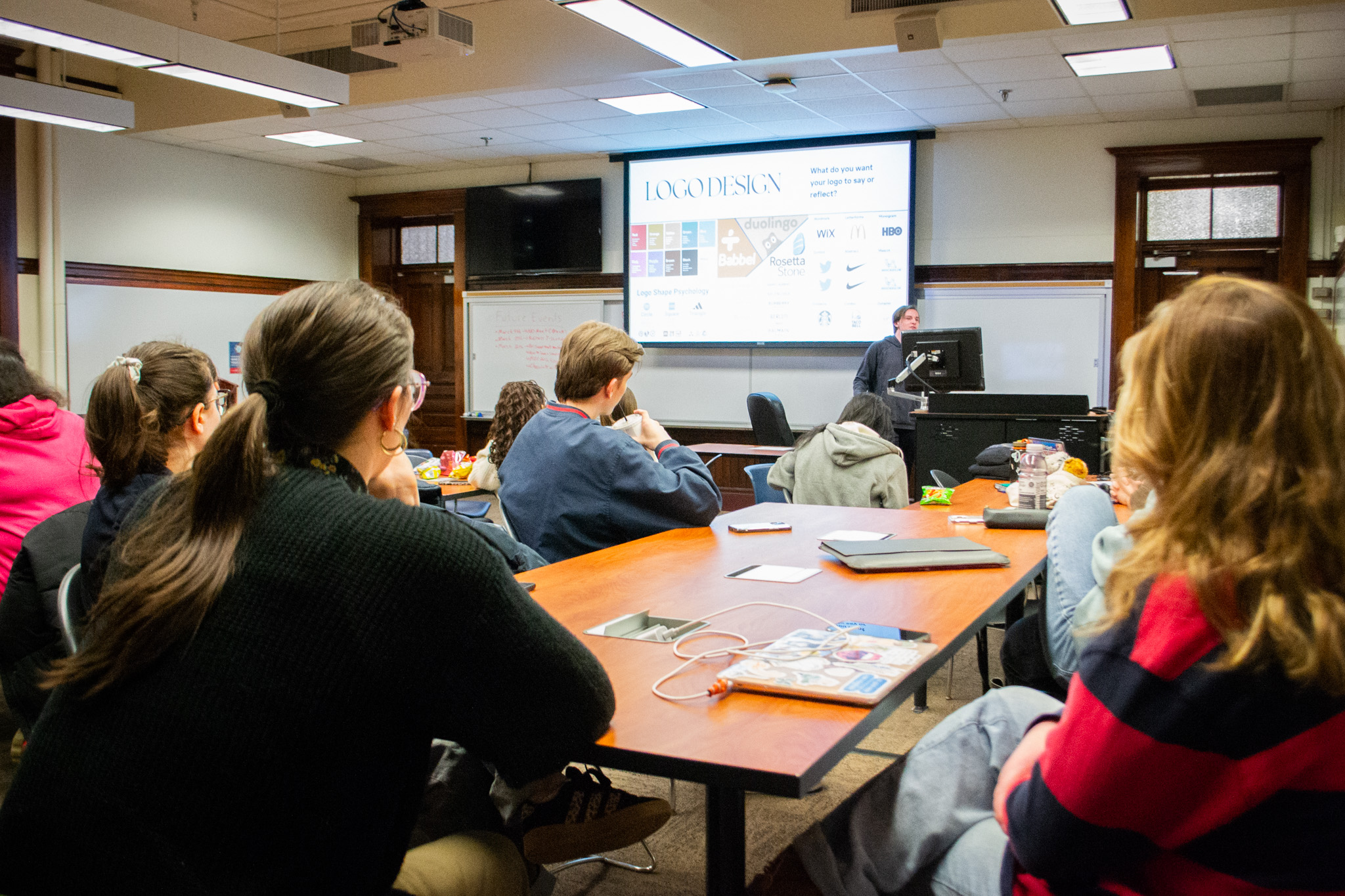 students sit at tables while student gives presentation