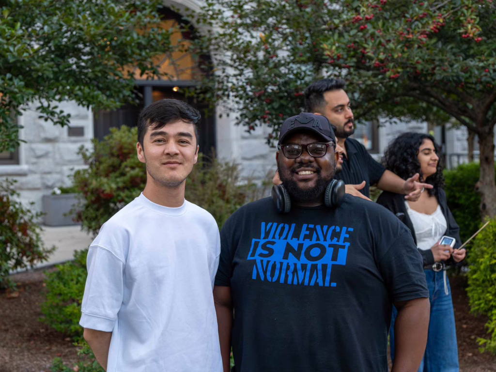 Students at fire pit night. One wears a tshirt that says 'Violence is not normal.'