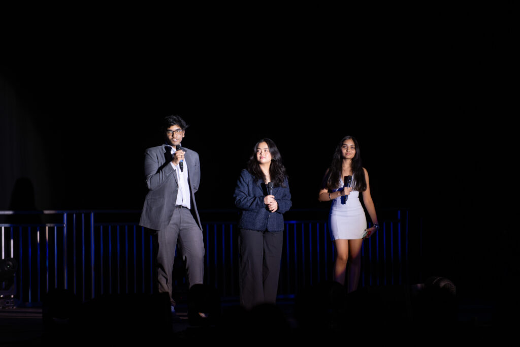 three people on stage with microphones