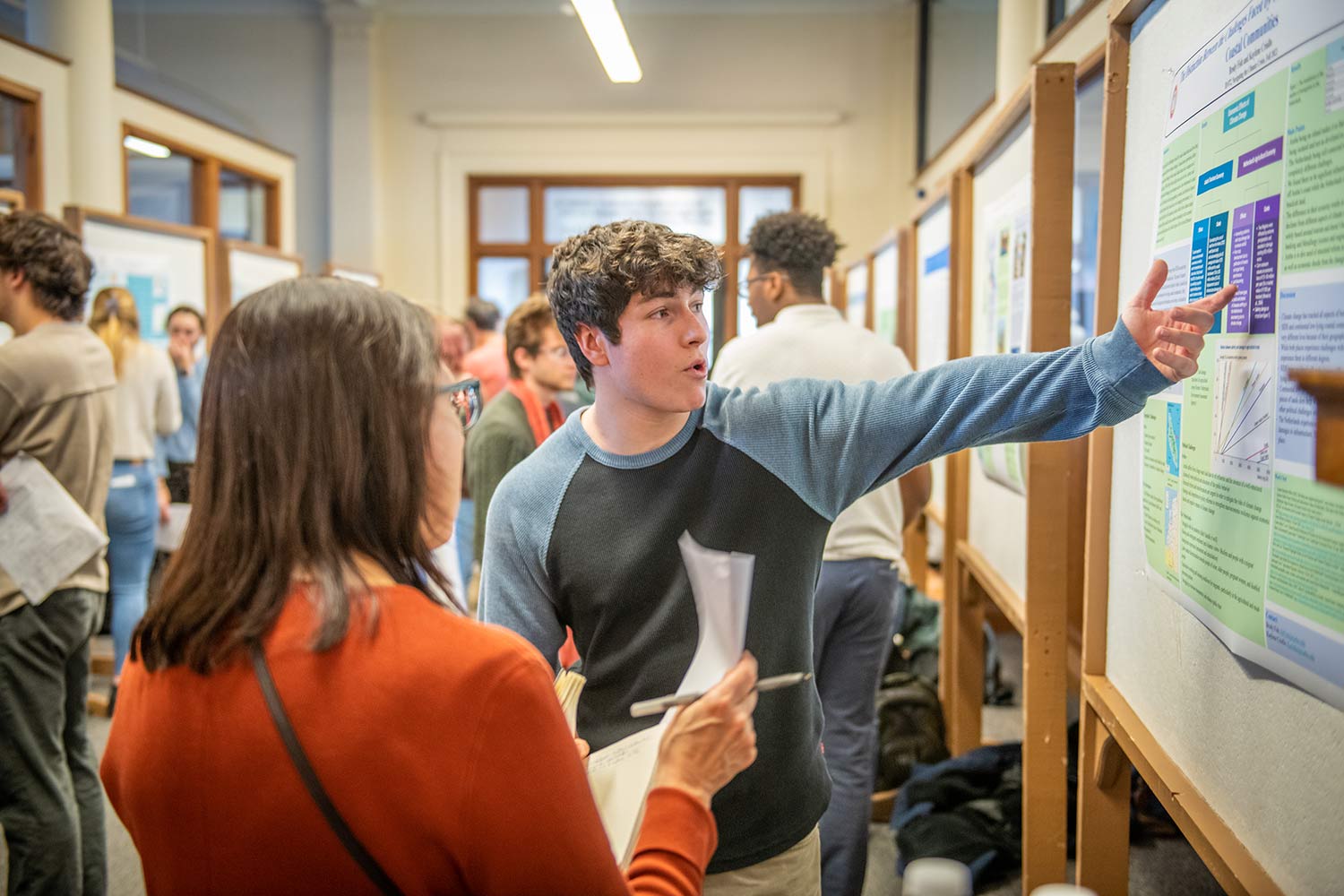 A student explains a research project geography postering event
