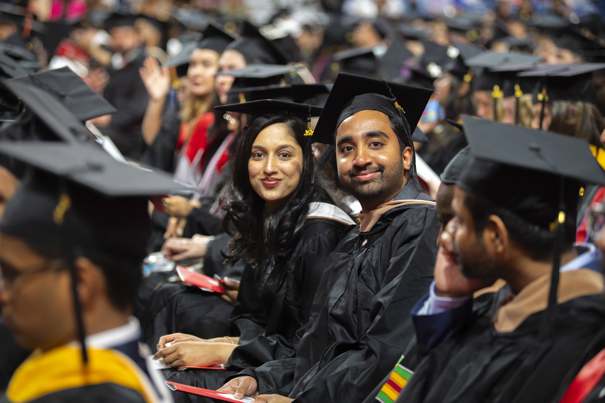 two students look at camera during commencement