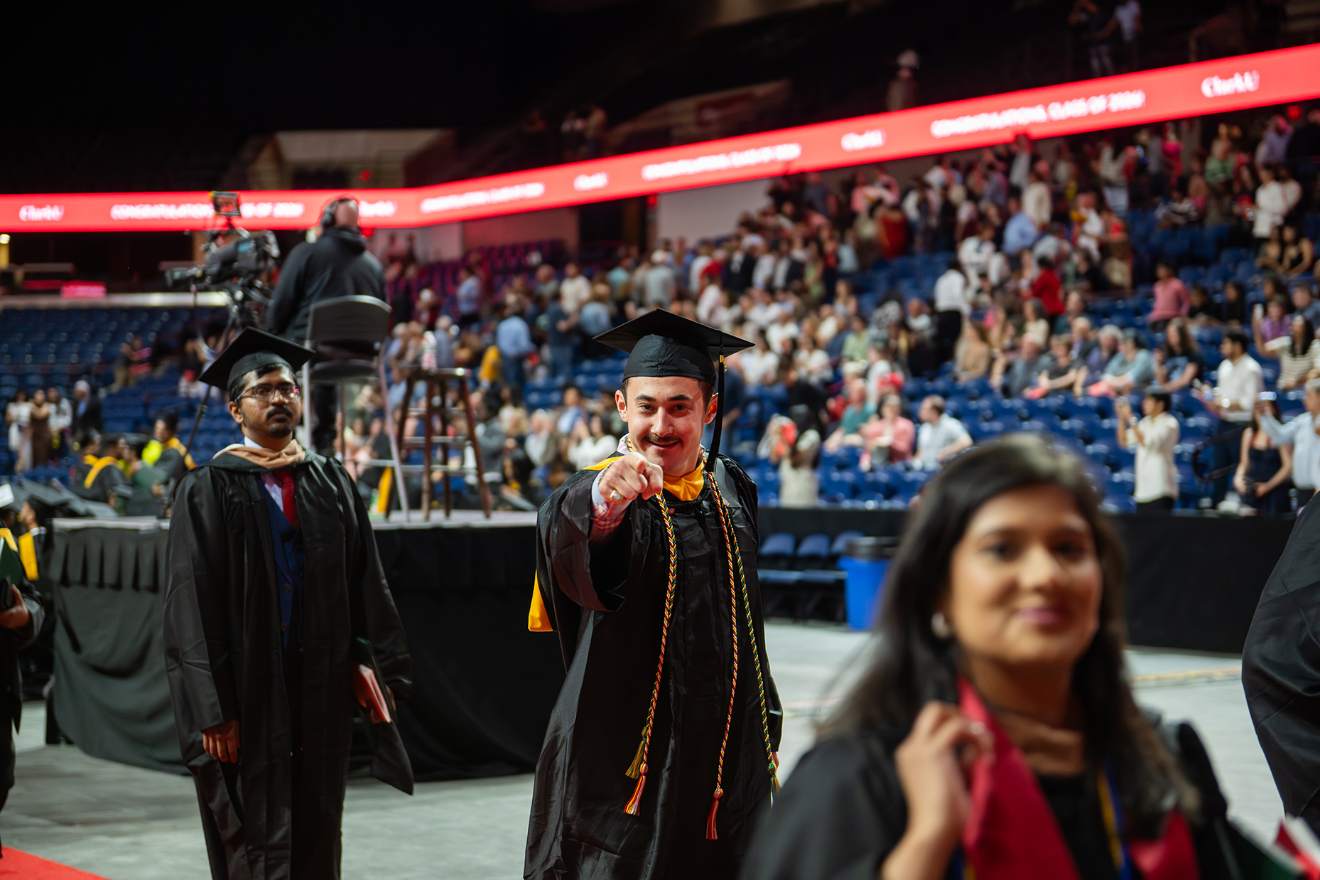 Student points at camera during Clark University commencement