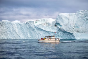 Tourist boat visiting iceberg off Greenland