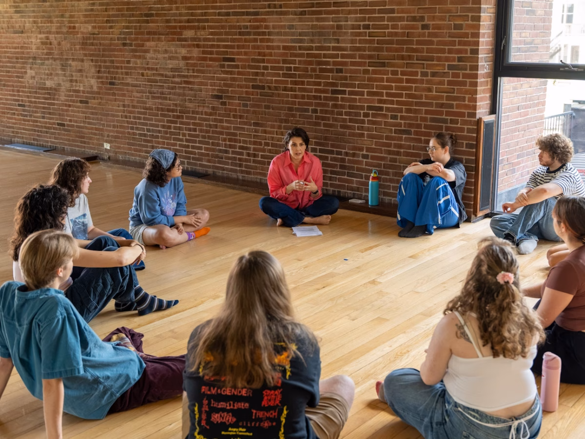 students and actor sit in circle