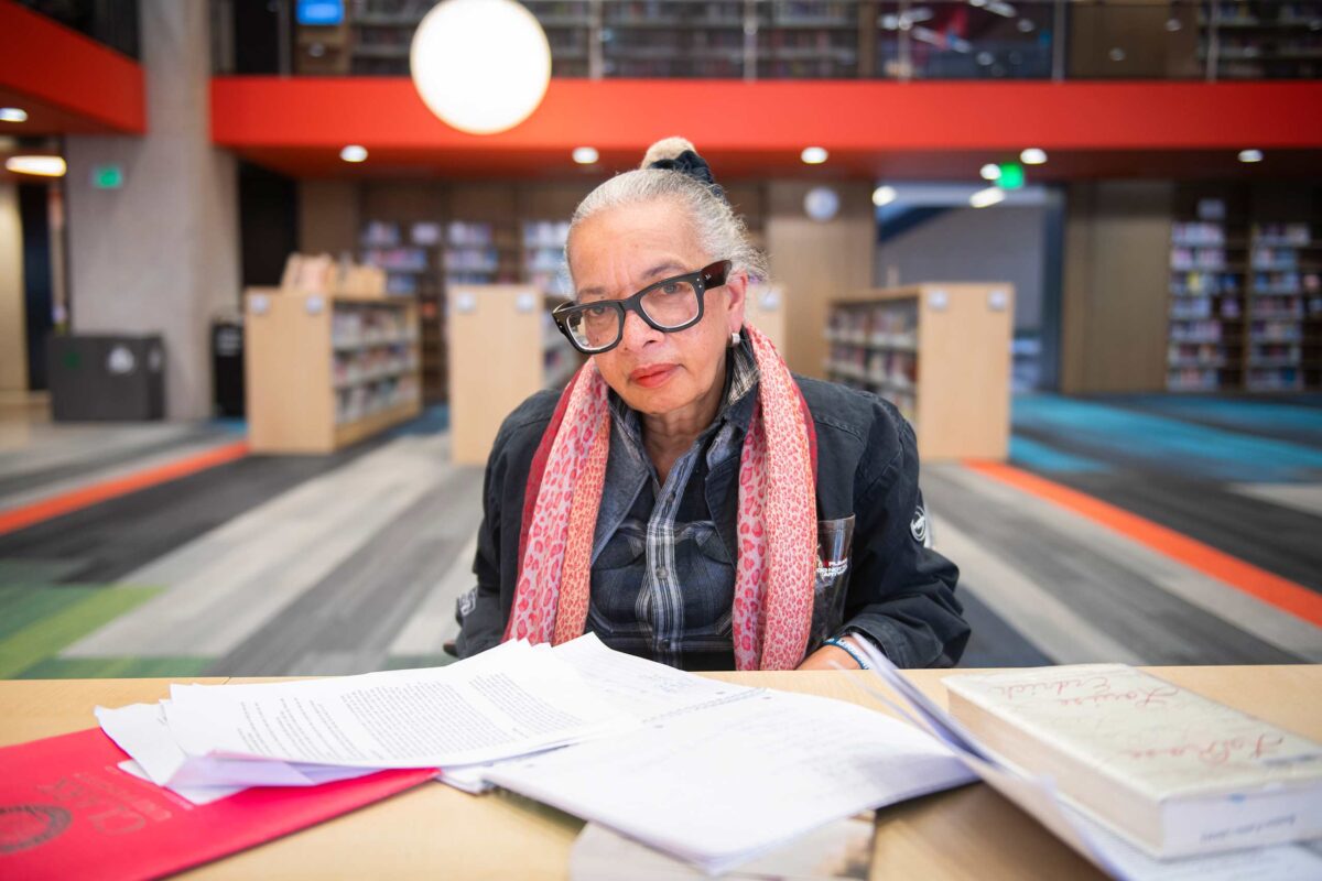 Jackie Scott seated in front of reading materials in the Boston Public Library