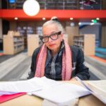 Jackie Scott seated in front of reading materials in the Boston Public Library