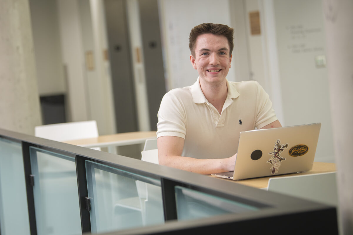 student poses for photo with laptop